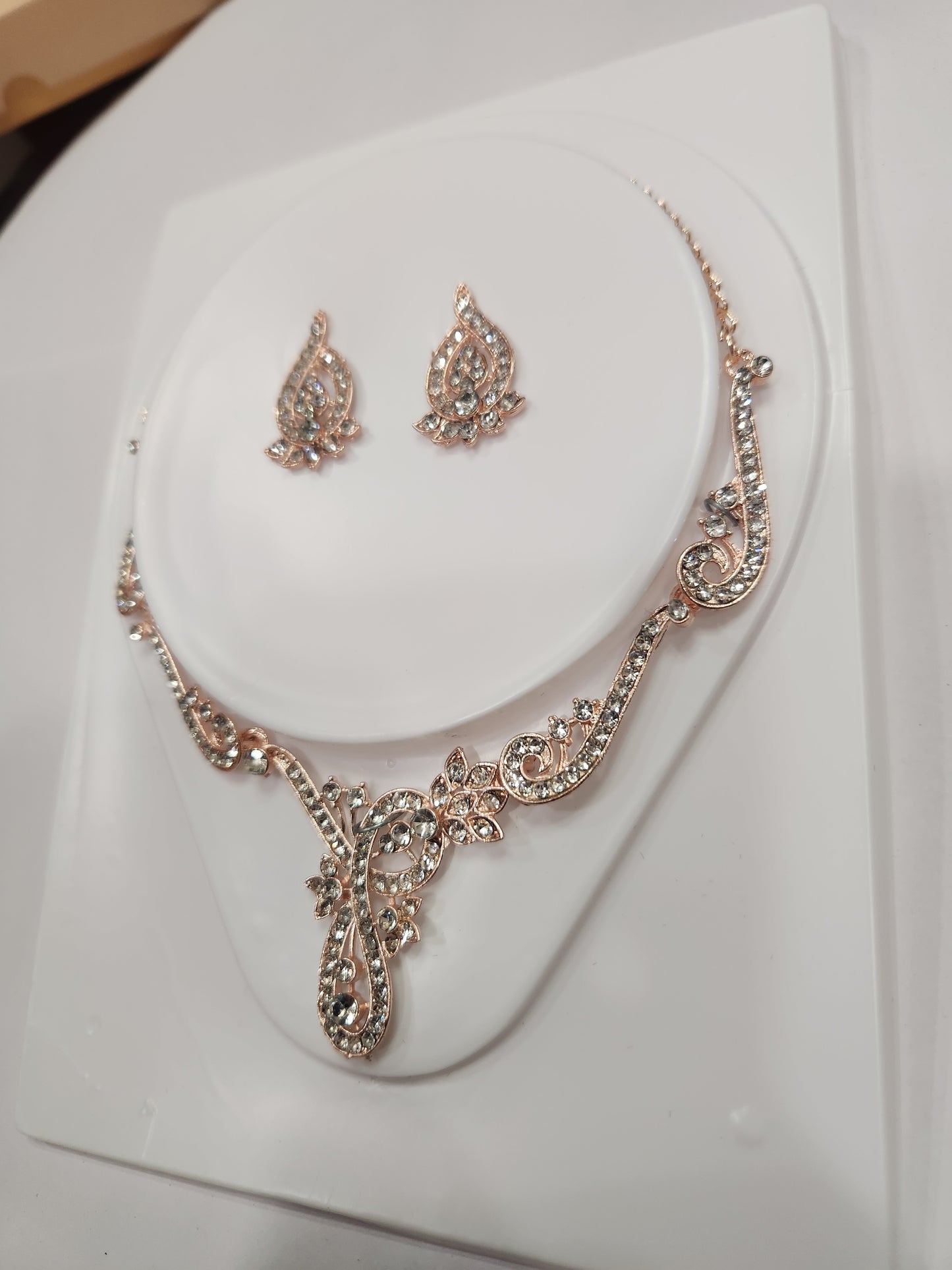 Elegant asymmetric white rhinestone necklace set with drop-shaped earrings, perfect for any attire.